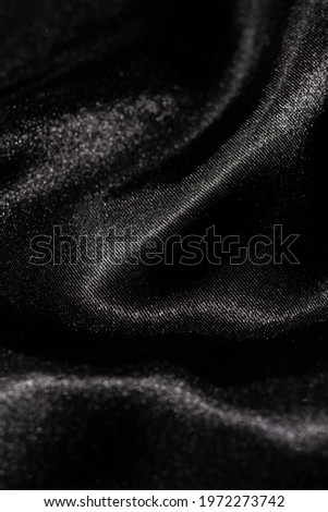Abstract black silk fabric texture background. Cloth soft wave. Creases of satin