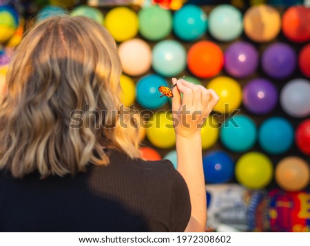 A female paying shooting range with colorful balloons at the amusement par Royalty-Free Stock Photo #1972308602