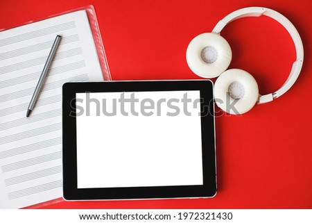 Top view open music book, headphones and a pen on a red background. mock up for a music lessons