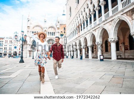 Couple of tourists visiting Venice, Italy - Boyfriend and girlfriend in love running together on city street - People, love and holidays concept Royalty-Free Stock Photo #1972342262