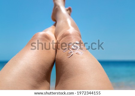 A woman smears her feet with sunscreen. Selective focus. People.