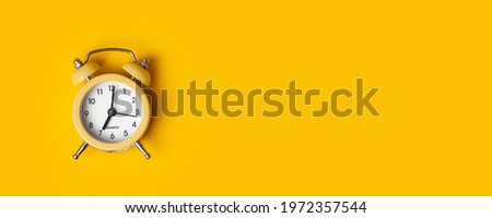 Top view of the yellow alarm clock on the yellow background with a free space for text. Getting up early in the morning. Wake up with a great mood Royalty-Free Stock Photo #1972357544