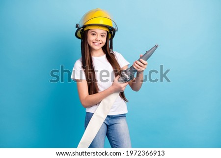Photo of young girl happy positive smile wear helmet firefighter hold water hose isolated over blue color background