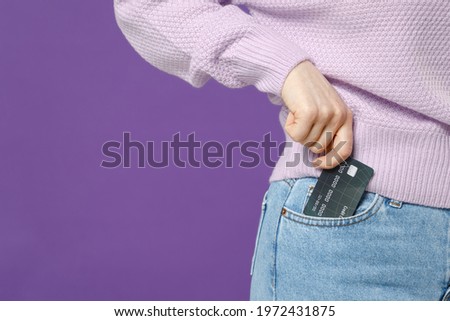 Close up cropped photo portrait shot student caucasian woman 20s wearing purple knitted sweater hold credit bank card put in jeans pocket isolated on violet background studio. People lifestyle concept Royalty-Free Stock Photo #1972431875