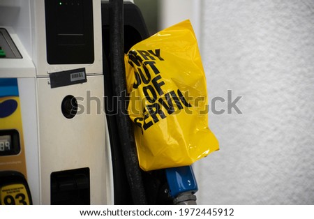 An empty pump at a gas station is covered with a yellow plastic bag following a cyber attack on the Colonial Pipeline.  Royalty-Free Stock Photo #1972445912