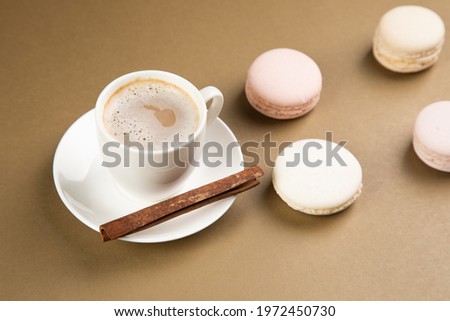 macarons and coffee with cinnamon on a gray background.