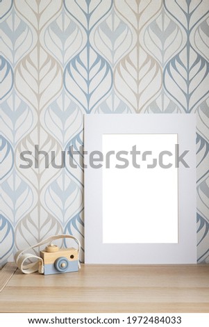 White frame mock up for photo, print art, text or lettering, with kids room decorations and toys. Blank frame on wooden table side view