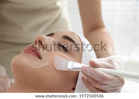 Young woman during face peeling procedure in salon Royalty-Free Stock Photo #1972500506