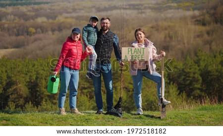 Portrait of a family of volunteers with children before planting a tree in nature