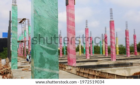 Curing cement poles with plastic. Green and pink plastic concrete columns are wrapped to control the moisture in the posts and complete the hydration for high durability. Close focus on the subject