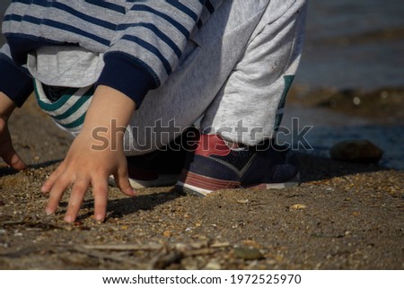 little boy playing with sand by the water 
