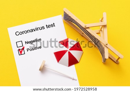 A form with positive results of the coronavirus test and inverted toy accessories for relaxation on a yellow background, a concept on the topic of spoiled vacation.