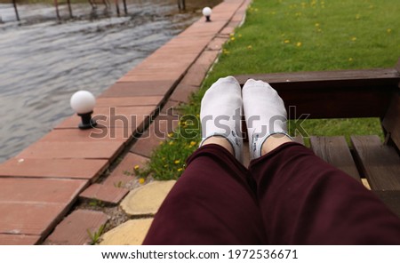 man resting on a bench near a pond, legs close up