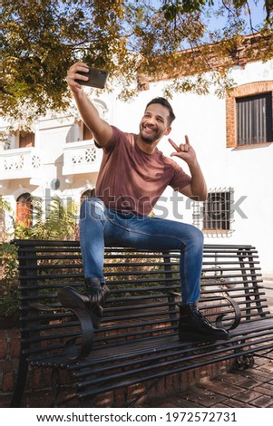 Handsome man taking a photo, showing happiness on a bench in the colonial city of Santo Domingo
