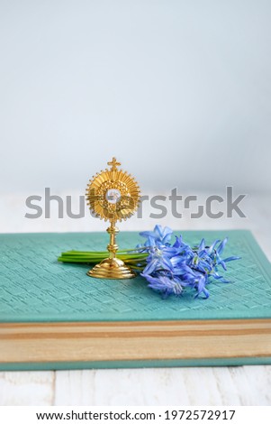 symbol of Catholic Sacrament of Communion, bible book and flowers on table. Eucharist, first communion, Christianity religion, faith in God. Church holiday concept. Golden JHS christogram