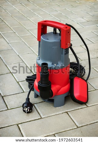 Household submersible pump with plastic housing  on stone floor of courtyard Royalty-Free Stock Photo #1972603541