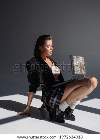 Young business woman working online. Freelance and remote work concept. Creative image. Fashionable elegant girl working on laptop and sitting on the floor. contrast lighting Royalty-Free Stock Photo #1972634018