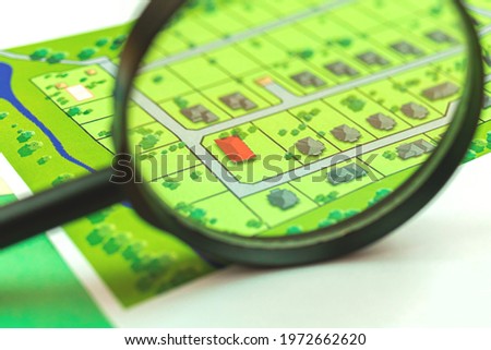 Search property with magnifying glass, office desk with map, real estate with new house photo