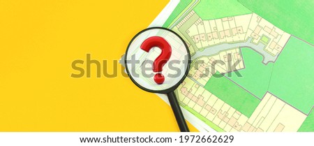 Concept of real estate search, magnifying glass with question mark, cadastral map, choose a building plot of land for house construction photo