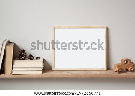 11x14 thin wood horizontal frame mockup for art and quotes, sitting on a wooden shelf. Vintage stack of books, old toy car and pine cones as props.