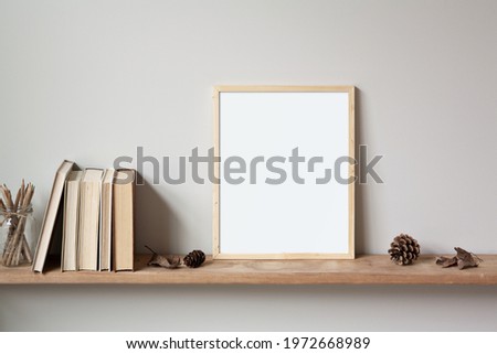 11x14 thin wood vertical frame mockup for art and quotes, sitting on a wooden shelf. Vintage stack of books, autumn leaves, pine cones and a glass jar of pencils as props.