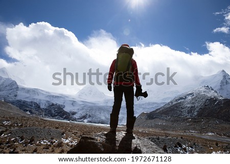 Woman hiker with camera in winter high altitude mountains