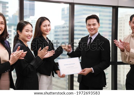 Group of Asian business corporation team celebrating together in the meeting room with CEO given certificate to the branch manager while the rest of employees are applauding (with fake certificate) Royalty-Free Stock Photo #1972693583