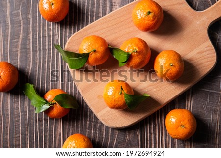 Fresh small tangerines with green leaves on  wooden table