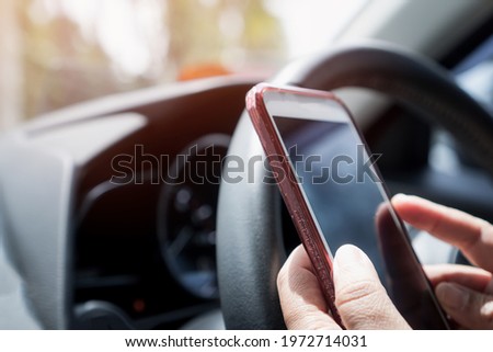 Driver driving car and hands using smartphone apps for searching maps or calling to friend on steering wheel. Mockup screen for text background
