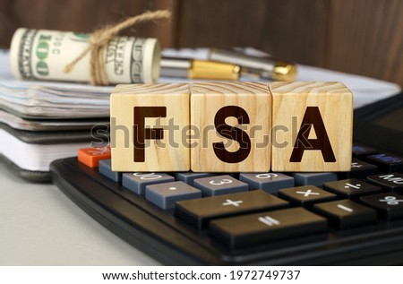 Finance and economics concept. On the table are money, a calculator, a notebook and cubes with the inscription - FSA
