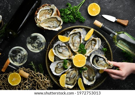 Bottle of aged wine and fresh oysters on a dark kitchen table. Seafood. Top view. Flat lay. Royalty-Free Stock Photo #1972753013