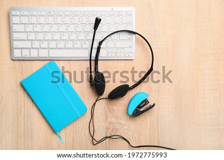 Headset, notebook and keyboard on table of technical support agent