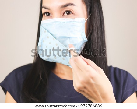 Close up image of Asian woman wearing  blue  polka dot cloth mask on medical face mask  for better protection  from covid-19 outbreak. Double face masks for covid19 protection.