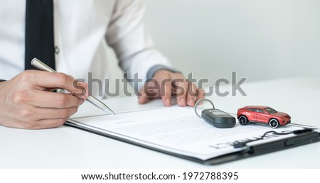 Car dealer businessman signing car insurance document or lease paper. Car loan and insurance concept.