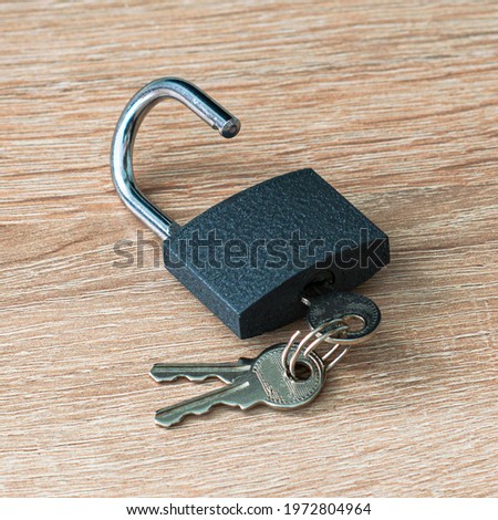 open iron padlock with keys in the keyhole on the wooden surface concept prohibition security restriction High quality photo