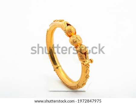 Golden bangle with beautiful work side view ideal for wedding isolated on white background. Gold jewellery stock photo. Royalty-Free Stock Photo #1972847975