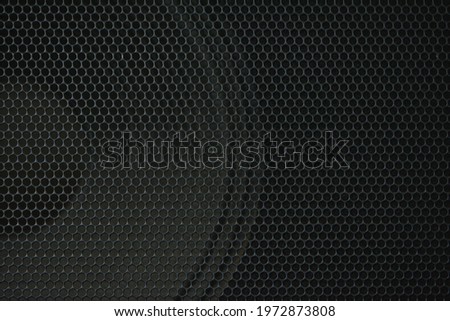 Close-up of a dark speaker grille with a speaker in the background Royalty-Free Stock Photo #1972873808
