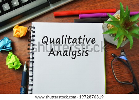 Selective focus of marker pen, scramble of paper, spectacle, and notebook written with QUALITATIVE ANALYSIS. Royalty-Free Stock Photo #1972876319