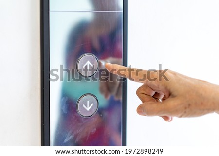 Asian old woman hand points to the button of elevator.