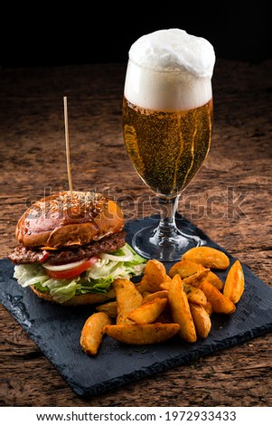 Set of hamburger beer and french fries. A standard set of drinks and food in the pub, beer and snacks. Dark background, fast food. Traditional american food. burger, potato and beer set