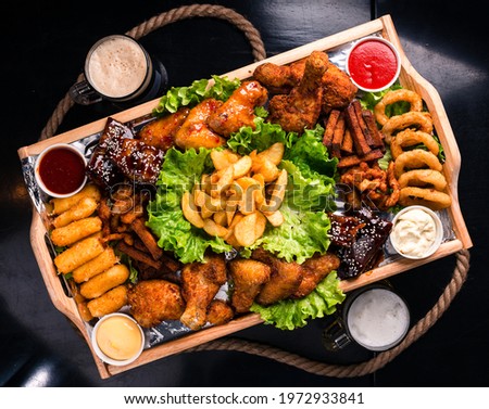 Large beer plate, large set of beer snacks. assorted snacks deep-fried beer. Food for a holiday for a large company. hot meat snacks for beer served on wooden dish board top view, flat lay Royalty-Free Stock Photo #1972933841