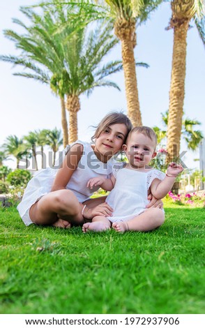 The girl's children are sitting under a palm tree. Selective focus. Nature.
