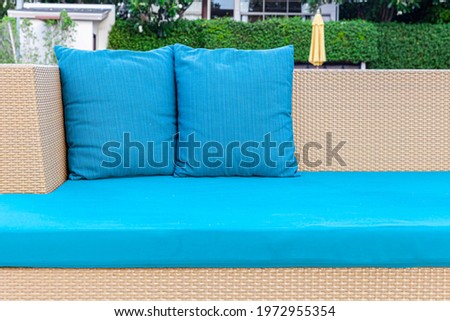 Long brown wicker sofa and blue cushions and cushions placed on the lawn