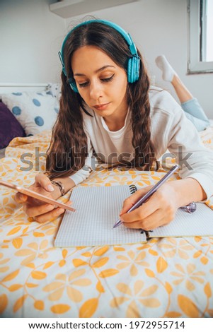 Beautiful woman listening to music and using a cellphone in her bed.