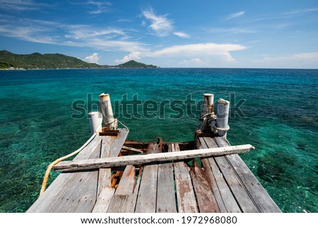a broken wooden bridge port on beautiful tropical ocean and mountain blue sky