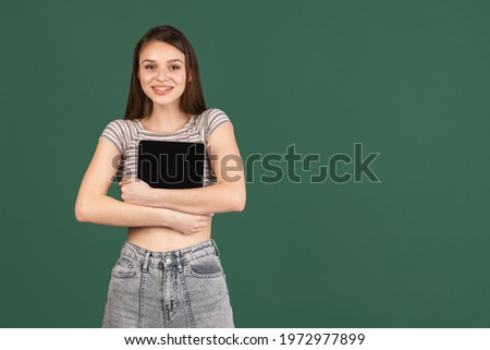 Young Caucasian girl with digital tablet isolated on green background.