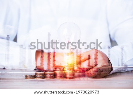 double exposure image concept, hand holding ligh blub coins idea business industrial technology future plant and enegry graphic design. Oil, gas and petrochemical refinery factory with background.