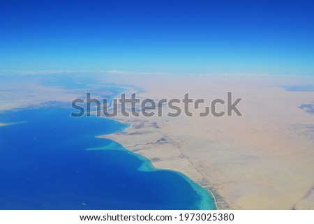 A beautiful aerial view from above from the plane showing the land and the sea
