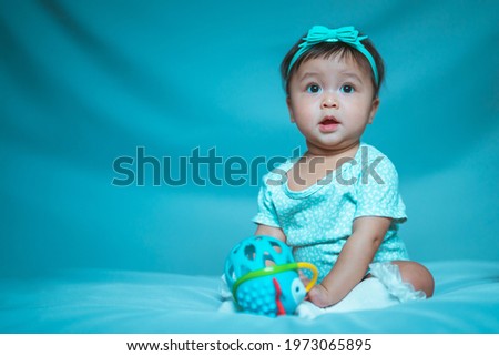 Portrait of a cute 6 month old baby, boy or girl, with toy 
