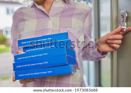 Close Up Of Woman Bringing Home Supply Of Covid-19 Rapid Antigen Self-Testing Kits Opening Front Door Royalty-Free Stock Photo #1973083688